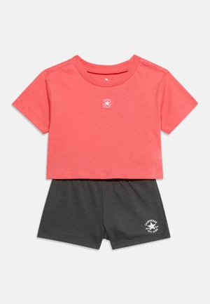 Ensemble t-shirt court corail à manches courtes et short gris foncé avec logos blancs Converse All Star sur les deux pièces.