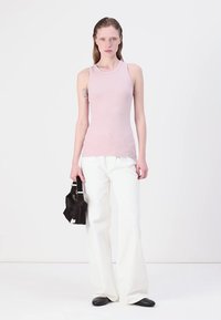 Light pink sleeveless top, white wide-leg pants, and black flat shoes. Black handbag with contrasting white hardware detail.