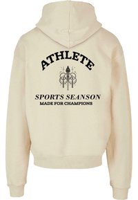 Beige hoodie met een capuchon, geribbelde manchetten en een geribbelde tailleband. Zwarte tekst met de woorden "ATHLETE", "SPORTS SEASON" en "MADE FOR CHAMPIONS" met grafische details.