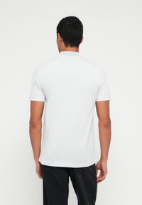 Rövid ujjú világosszürke pólóing klasszikus gallérral és testhezálló szabással, sima anyaggal.