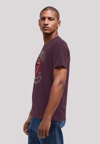 Maroon cotton T-shirt featuring a large Rolling Stones logo with red lips graphic. Short sleeves, crew neck, relaxed fit.