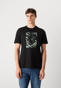 Zwarte t-shirt gemaakt van katoen met een jungle-thema graphic van een zwarte panter en loof. Ronde halslijn, korte mouwen, regular fit.