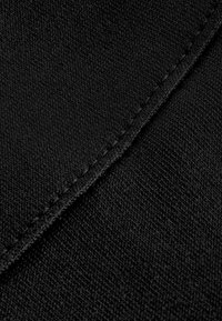 Black fabric close-up featuring a textured finish and visible stitching along the edge, highlighting its woven pattern and smooth surface.