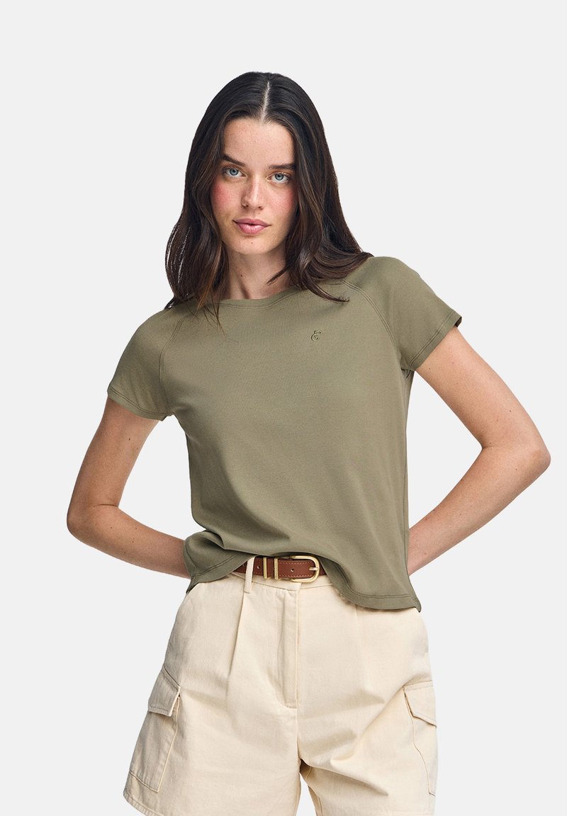 T-shirt verde oliva a maniche corte con scollo rotondo e un discreto dettaglio del logo sul petto, abbinato a pantaloni cargo beige chiaro.