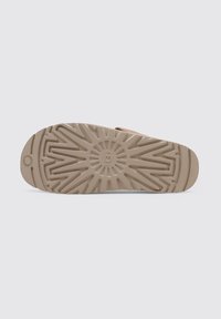Suola della scarpa in gomma beige chiaro con un motivo testurizzato caratterizzato da scanalature radiali e creste, progettata per garantire presa e trazione.