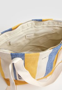 Torebka typu tote w paski o niebieskim, żółtym i białym plecionym wykończeniu. Zamek błyskawiczny, wewnętrzna podszewka w kolorze kremowym oraz wewnętrzna kieszeń. Wytrzymałe uchwyty.