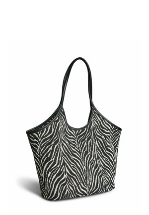 Bolsa tote a rayas de cebra en blanco y negro con asas y ribetes negros, de pie en posición vertical sobre un fondo blanco.