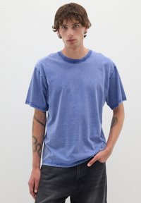 Korte mouwen blauwe crew neck t-shirt met een gemêleerde textuur. Heeft een ontspannen pasvorm en subtiele stikdetails langs de naden.