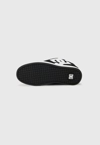Sorte og hvide skate-sko med en tekstureret gummisål. Har et fremtrædende logo, bred krop og en kontrastfarvet detalje.