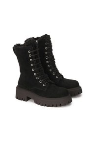 Las botas de tobillo de ante negro presentan un cierre de cordones con ojales de metal, una suela gruesa y texturizada, y un lujoso acento de piel de oveja alrededor del cuello.