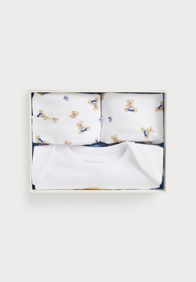 Σετ δώρου μωρουδιακών ρούχων με λευκό φορμάκι και καπέλο που φέρουν μικρές αρκουδάκια ντυμένα με μπλε ρούχα και κόκκινες ριγέ μπλούζες.