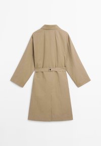 Manteau beige avec un col, des manches longues et une ceinture à nouer à la taille. Texture lisse, longueur genoux, sans motifs ni accents visibles.