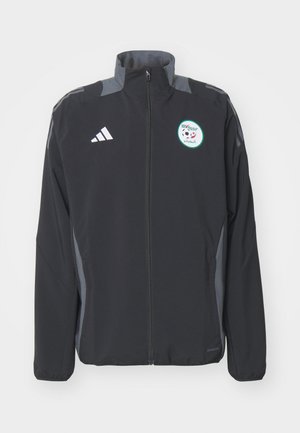Giacca atletica nera con accenti grigi, zip completa, colletto alto, con un logo rotondo di calcio e marchio a tre strisce sulle maniche.