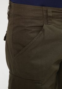 Kaki cargoshorts i bomullsmaterial. Har sidofickor, sydda detaljer och en slät textur.