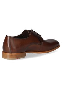 Chaussure en cuir marron avec une finition lisse, bout arrondi et côtés texturés. Dispose d'une semelle en bois et de trois œillets pour les lacets.