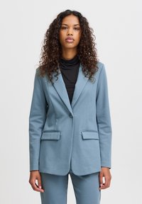 Lichtblauwe, op maat gemaakte blazer met notched revers, twee voorzakken en een enkele knoopsluiting. Gladde, gestructureerde stof.