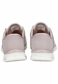 Baskets de sport roses claires avec une tige en mesh, un col rembourré et une semelle en caoutchouc blanc. Elles présentent un design texturé et une étiquette de marque à l'intérieur.