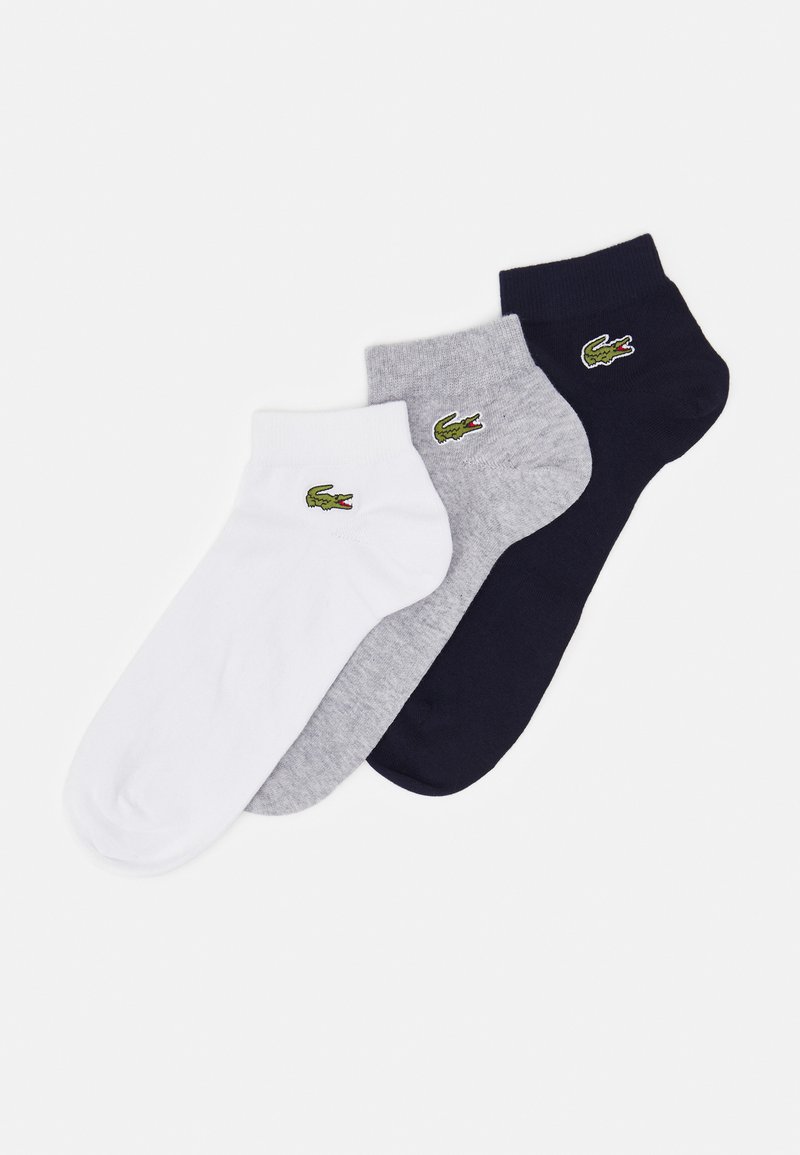 Tres pares de calcetines bajos en blanco, gris y azul marino, con un pequeño logo de cocodrilo verde. Fabricados con un material suave y elástico.