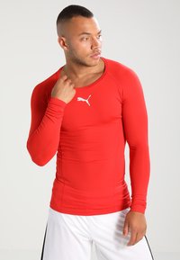 Rød langermet treningstrøye laget av elastisk materiale med rund hals og hvit Puma-logo på brystet.
