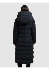 Cappotto lungo imbottito di un blu navy scuro con un design trapuntato, cappuccio oversize e taglio dritto, caratterizzato da una texture liscia e un discreto marchio sul retro.