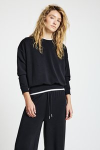 Sweat-shirt noir décontracté à manches longues avec poignets côtelés. Présente un ourlet rayé blanc et une coupe décontractée. Tissu doux sans motifs visibles.