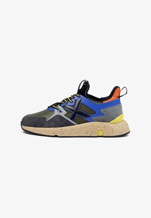 Sportieve sneaker met een mix van grijze, blauwe en groene stoffen, voorzien van een gespikkelde beige zool en felgele accenten. Versterkt ontwerp van de hiel.