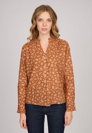 Chemise marron à manches longues avec un petit col, ornée d'un motif cachemire crème, avec un devant boutonné et des poignets plissés. Assortie à un jean sombre.