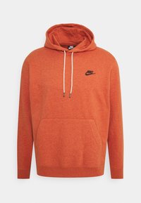 Orange hoodie i mjukt, strukturerat tyg, med en framficka, dragsko i huvan och en liten svart Nike-logga på bröstet.
