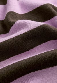 Gestreepte gebreide stof met afwisselend gedurfde tinten van lavendel en donkerbruin. Glad textuur met een zachte, flexibele val.