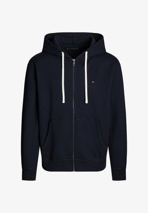 Marineblå zip-up hættejakke lavet af blødt stof, med snoretræk i hætten, to forlommer og en lille logo detalje på brystet.
