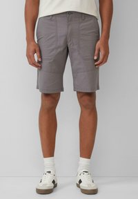 Shorts cargo gris en tissu léger, dotés de deux poches latérales, de panneaux couturés et d'une coupe droite. Associés à des baskets blanches.