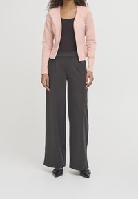 Ljust rosa skräddarsydd blazer, tillsammans med mörka vida byxor. Svart topp under och svarta spetsiga skor fulländar looken.