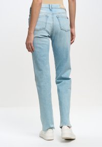Jeans de mezclilla azul claro con diseño de pierna recta, cinco bolsillos y una textura ligeramente desgastada. Presentan una cinturilla clásica y costuras mínimas.