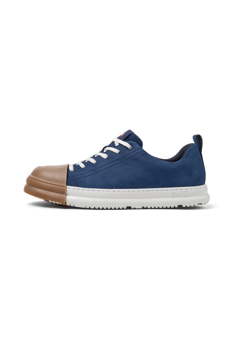 Zapatilla navy con puntera de goma color marrón, cordones blancos y suela texturizada, posicionada sobre un fondo liso para mayor visibilidad.