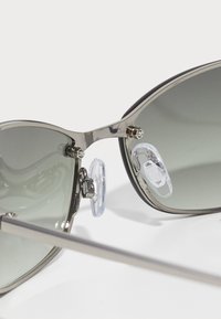 Metal frame sunglasses with gradient gray lenses, featuring clear nose pads and silver hardware accents. Sleek design with a curved shape.