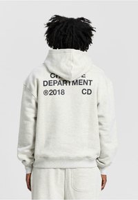 Light gray hoodie with a drawstring hood. Features bold black text on the back: "CREATIVE DEPARTMENT 2018 CD". Soft fabric texture.