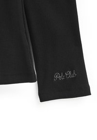 Maglietta nera a maniche lunghe con un design aderente. Presenta "Polo Club" ricamato in grigio all'orlo della manica. Tessuto morbido, dettagli minimalisti.