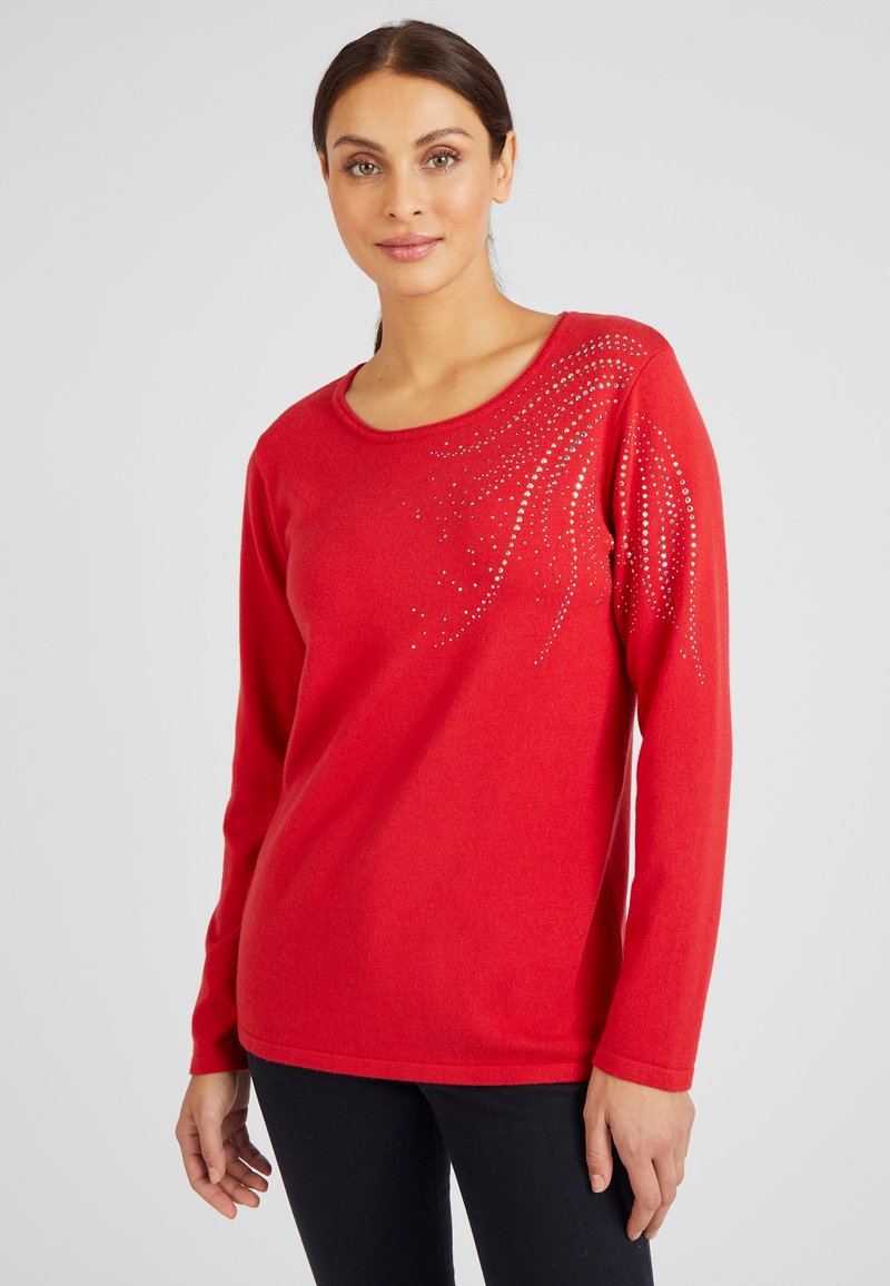 Rode trui met lange mouwen en een ronde halslijn, versierd met een patroon van zilveren rhinestones aan één zij. Zacht, gestructureerd stof.