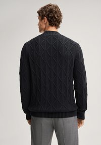 Schwarzer Strickpullover mit geometrischem Muster, gerippten Bündchen und Saum sowie Rundhalsausschnitt, aus dickem strukturiertem Stoff gefertigt.