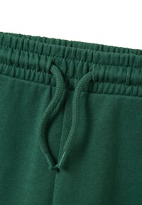 Groene sweatpants met een gestructureerde stof, voorzien van een elastische tailleband en trekkoord. Het algehele ontwerp is eenvoudig en casual.