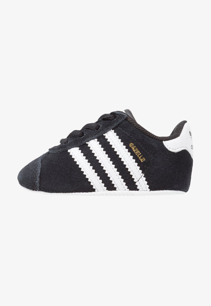 Sorte ruskinds sneakers med hvide zigzag-striber, struktureret stof, rund tå og hvid gummisål. Guldbrand på siden.