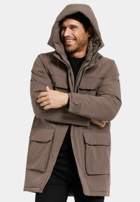 Brun vadderad parka-jacka med huva, som har flera framfickor, ett dragkedjestängning och en texturerad tyg.