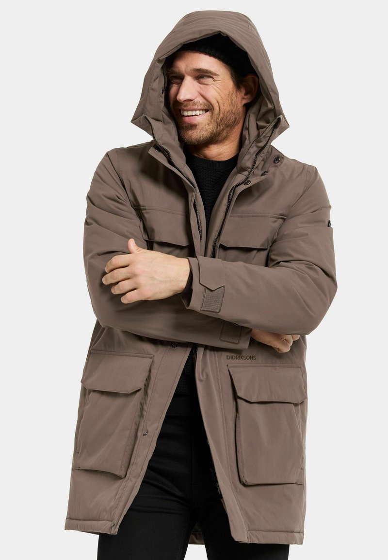 Brun vadderad parka-jacka med huva, som har flera framfickor, ett dragkedjestängning och en texturerad tyg.