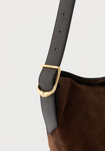 Brun ruskindstaske med sort læder justerbar rem og guldfarvet hjerteformet spænde.