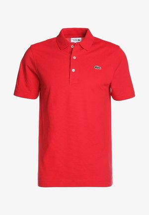 Polo rojo de manga corta Lacoste Sport con tres botones y logo de cocodrilo verde en el pecho izquierdo.
