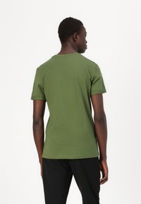 T-shirt verde de algodão com gola redonda e mangas curtas, apresentando uma textura suave e um design simples e clássico.