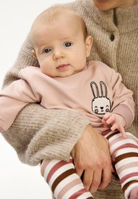 Ljusrosa sweatshirt med en kaninbild, kombinerad med randiga leggings i rosa, vitt och brunt. Mjukt, avslappnat tyg med lös passform.