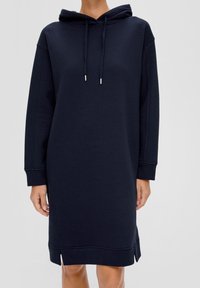 Marinblå huvtröja i klänningstyp, tillverkad av mjukt material, med långa ärmar, sidoflikar vid fållarna och dragskoaccent vid huvan.