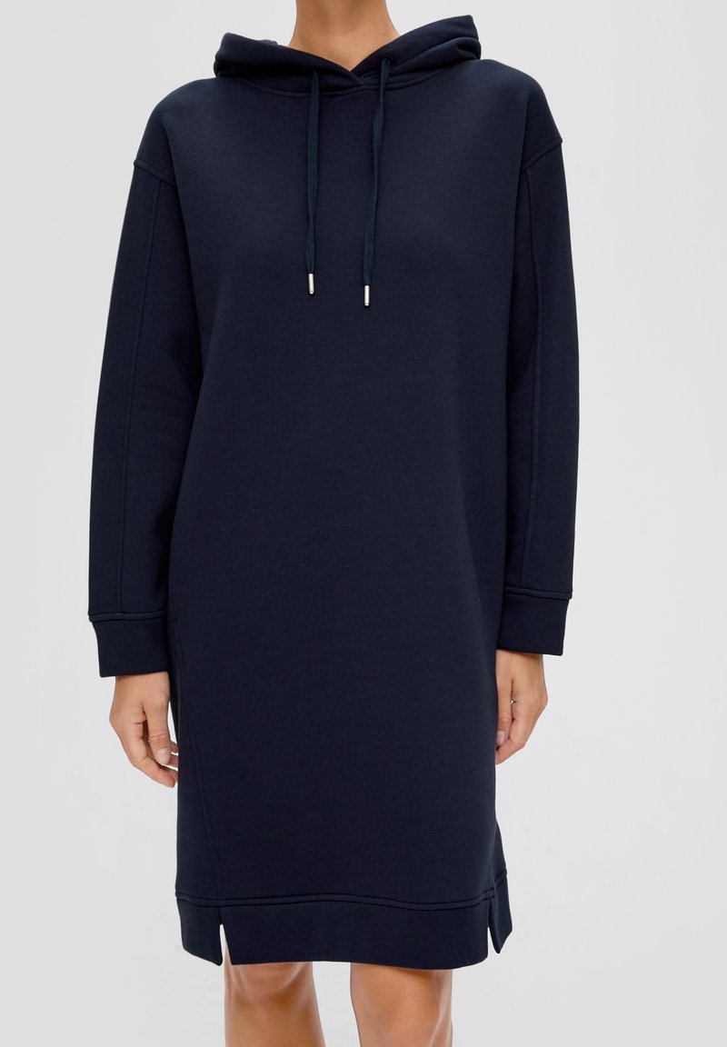 Marinblå huvtröja i klänningstyp, tillverkad av mjukt material, med långa ärmar, sidoflikar vid fållarna och dragskoaccent vid huvan.