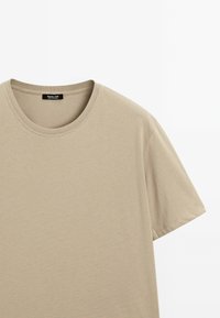 Beige Kurzarm-T-Shirt mit Rundhalsausschnitt, aus weichem Stoff hergestellt. Verfügt über eine glatte Textur und eine saubere Nahtführung ohne Muster.